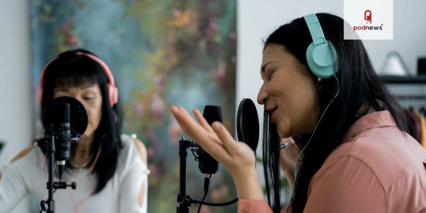 Two people talking into a microphone