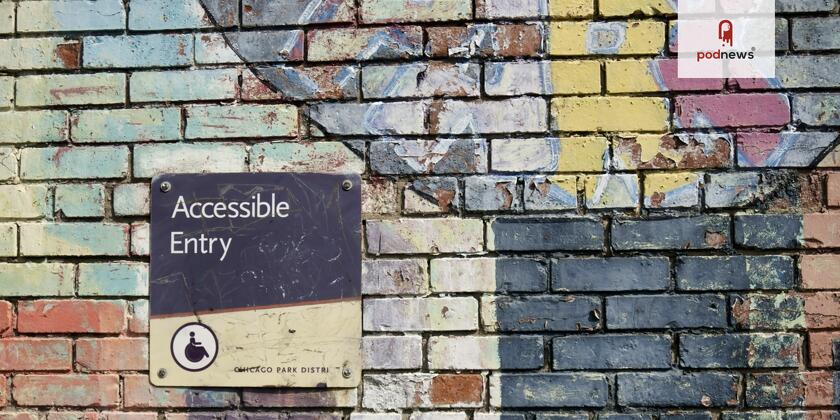 An old, scuffed, sign saying Accessible Entry, on a brick wall with colourful paint