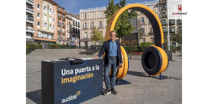 A man stands in front of a big pair of orange headphones