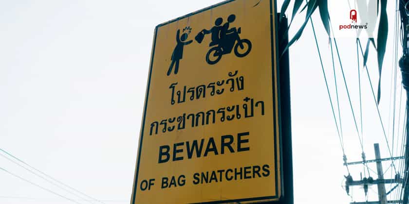 A yellow sign, in Thai and English, saying beware of bag snatchers