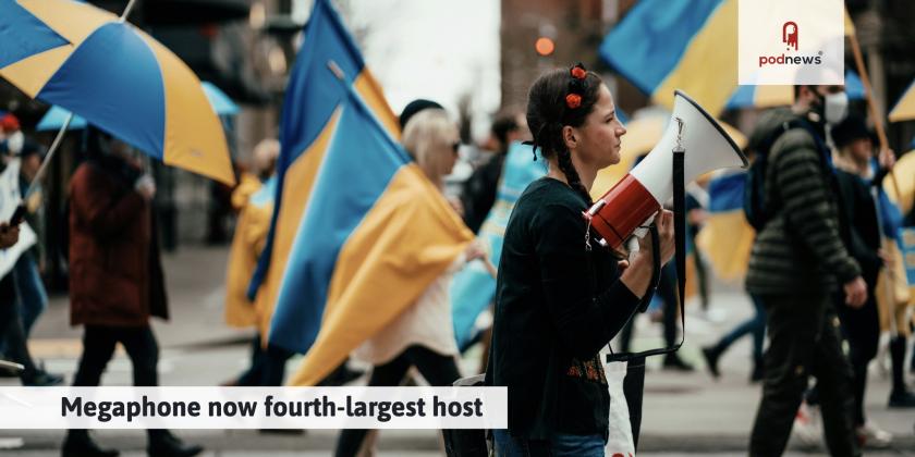 A woman holding a Megaphone with Ukranian flags behind