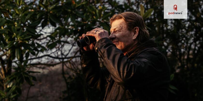 Sean Bean looks through binoculars at something, probably a bird