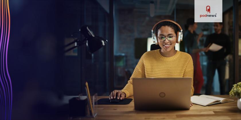 A woman wearing headphones smiles at her computer